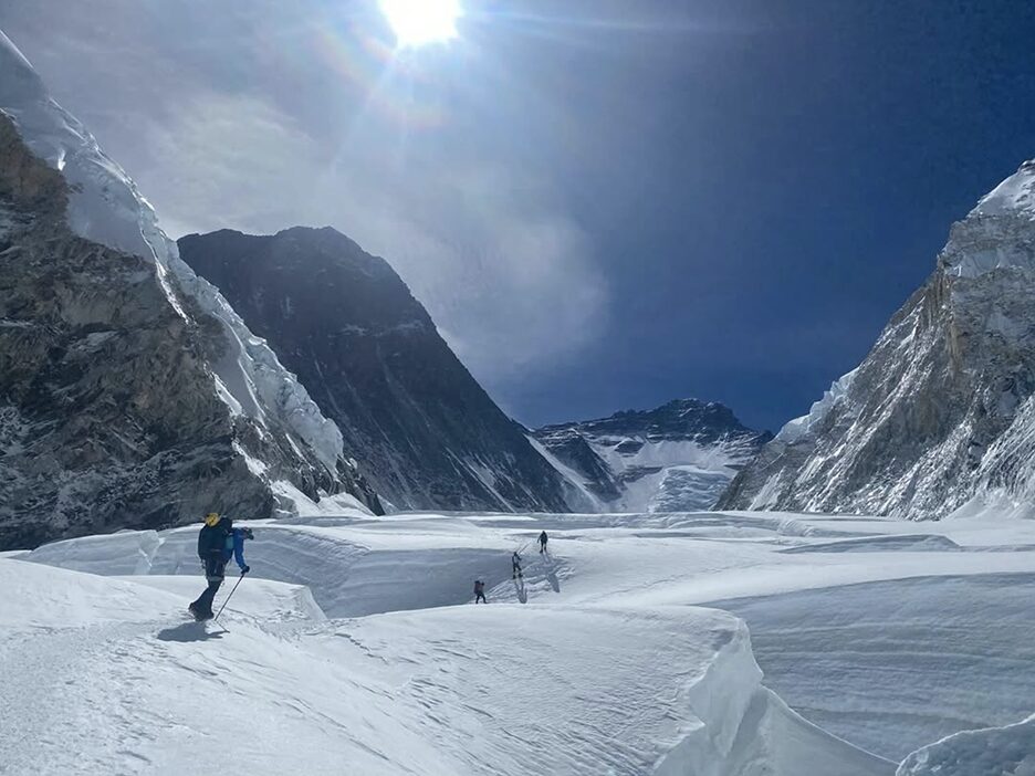 wide open mountain area with snow and a few backlit climbers